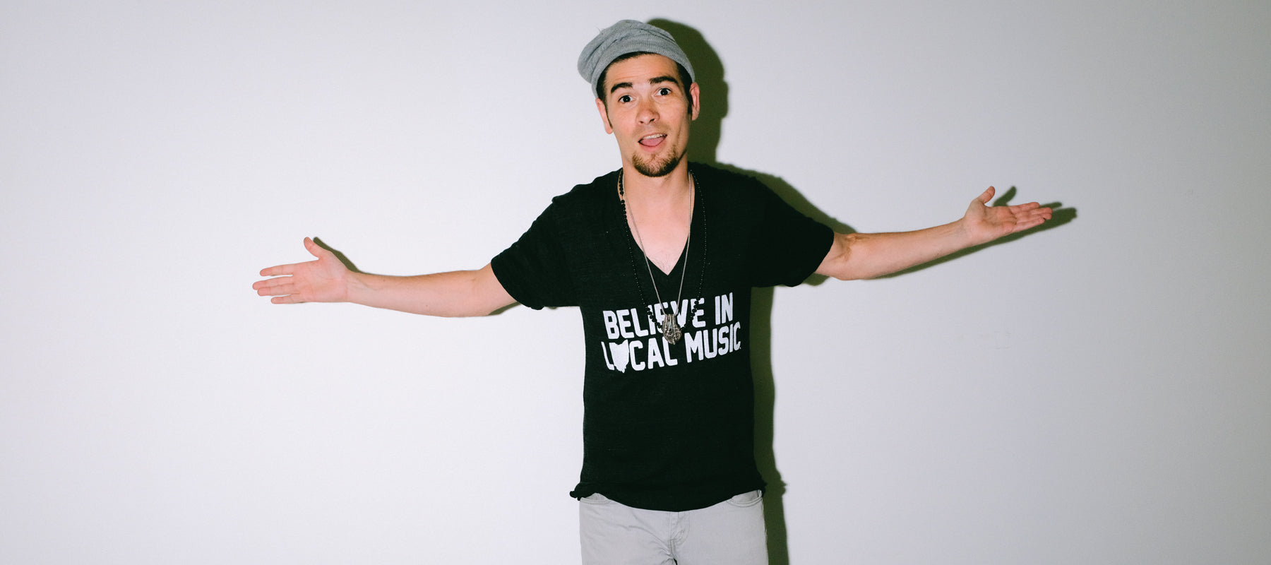 Believe In Local Music in White Print on a Black V-Neck T-Shirt as worn by model Joey Gurwin Homepage Header Mysterioso Rock Art